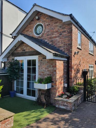 a brick house with a clock on the side of it at The Coach House Holiday Cottage, Southport in Southport