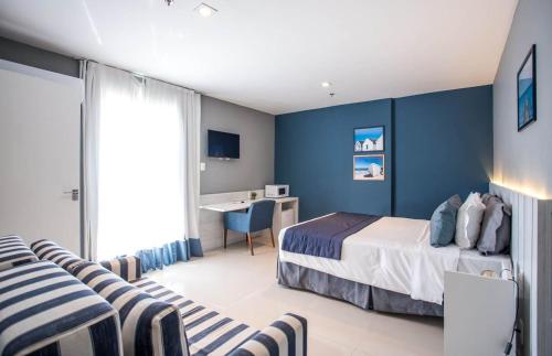 a bedroom with blue walls and a bed and a desk at Flat 402 in Cabo Frio 700m from the beach in Cabo Frio