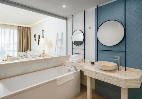 a bathroom with a tub and a sink and mirror at Siena Premium Retreat in Lozenets