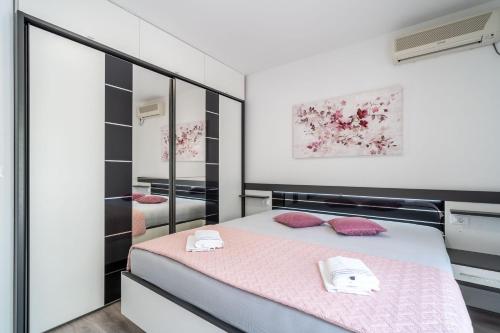 a bedroom with a bed with pink sheets and mirrors at Deluxe apartment in Mlini