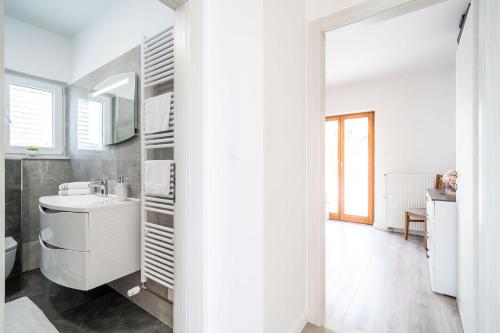 a white bathroom with a sink and a mirror at Deluxe apartment in Mlini