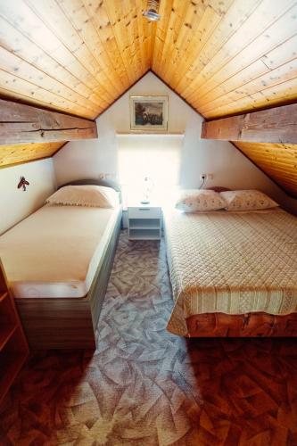 two beds in a room with a wooden ceiling at Zidanica Bahor in Črnomelj