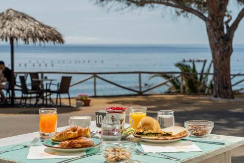 a table with plates of food and a view of the ocean at Hotel Ristorante La Conchiglia in Cala Gonone