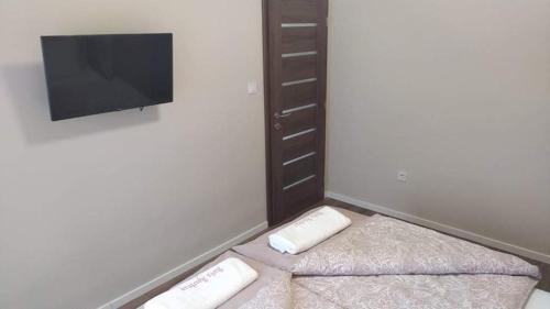a room with two beds and a flat screen tv at Barka Apartman in Nagykanizsa