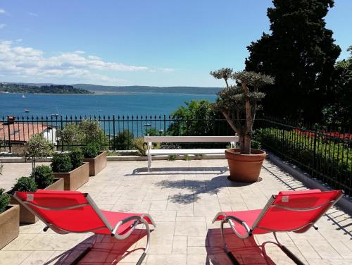two red chairs sitting on a patio overlooking the water at Apartments & Rooms Matos in Portorož