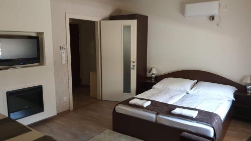 ハイドゥソボスローにあるKeller Arany Apartmanokのベッドルーム(ベッド1台、薄型テレビ付)