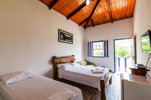 a bedroom with two beds and a wooden ceiling at Hotel Fazenda Serra da Irara in Corumbá de Goiás