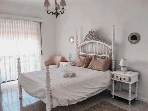 a bedroom with a white bed with a cat laying on it at Casa do gato branco in Furadouro