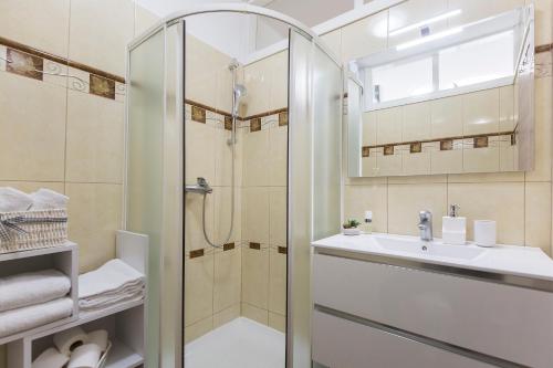 La salle de bains est pourvue d'une douche, d'un lavabo et d'un miroir. dans l'établissement Apartman Lungo Mare, à Rabac