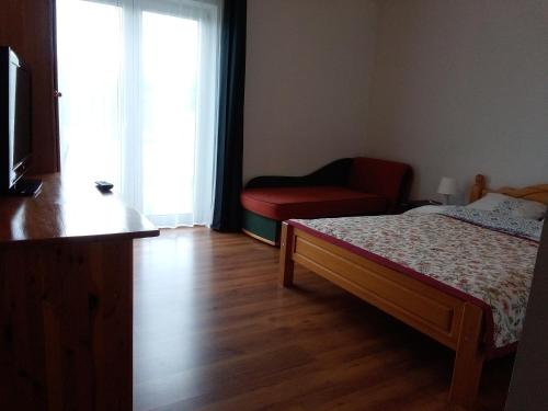 a bedroom with a bed and a chair and a window at Apartamenty 3D in Giżycko