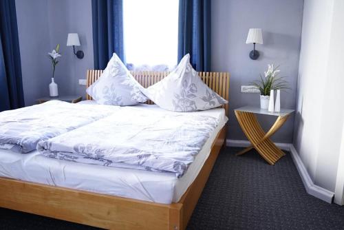 a bedroom with a bed with white sheets and pillows at Nordlicht Hollfeld in Hollfeld