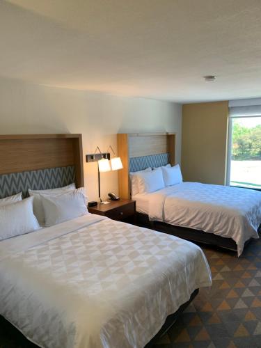 ein Hotelzimmer mit 2 Betten und einem Fenster in der Unterkunft Holiday Inn Baton Rouge-South, an IHG Hotel in Baton Rouge