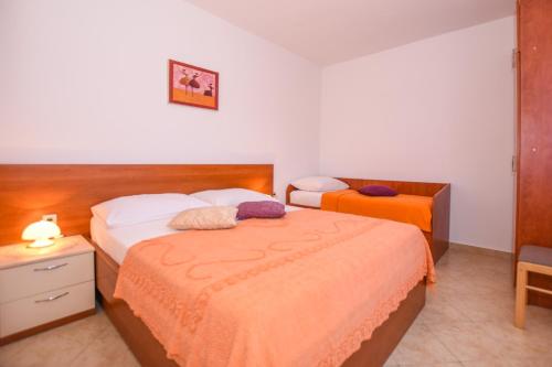 a bedroom with two beds and a table and a chair at APARTMANI MARIJA LJUBICA in Pag