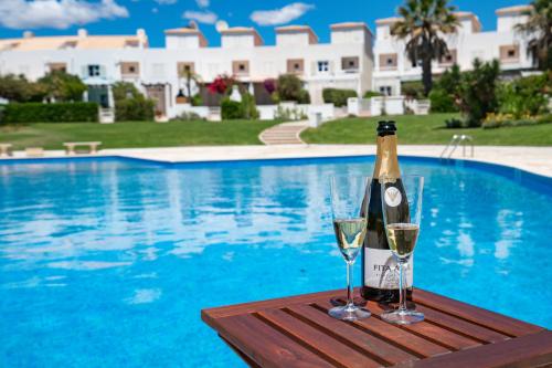 a bottle of champagne and two glasses on a table near a swimming pool at Beach villa with ocean view and rooftop cinema in Guia