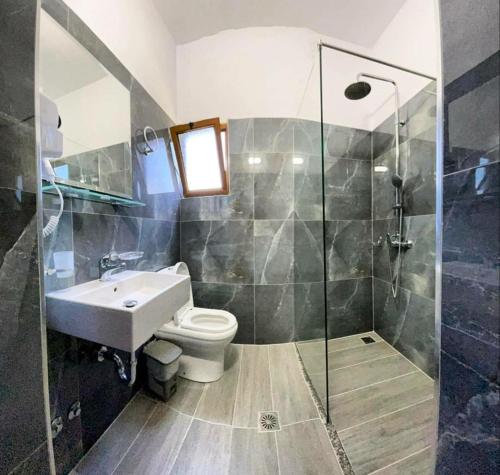 ein Bad mit einer Dusche, einem WC und einem Waschbecken in der Unterkunft Hotel Lula Ksamil in Ksamil