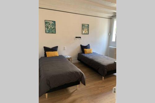 een slaapkamer met 2 bedden en een raam bij L’escapade : maison centre-ville avec cour in Saumur