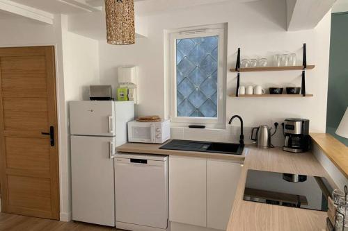 une cuisine avec un réfrigérateur blanc et une fenêtre dans l'établissement L’escapade : maison centre-ville avec cour, à Saumur