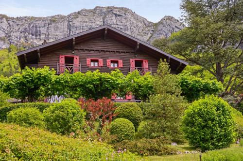 une maison en rondins avec des fenêtres rouges et une montagne dans l'établissement Grand Chalet 180 m2 - Welkeys, à Veyrier-du-Lac