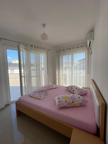 a bedroom with a large bed with purple sheets and pillows at Nimfeum Apartments in Shëngjin