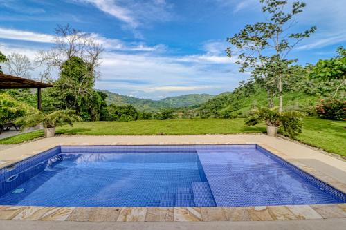 a swimming pool in a backyard with a mountain in the background at Casa La Cascada in Dominical