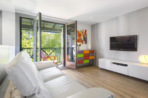 salon z białą kanapą i telewizorem w obiekcie Modern flat with three balconies in Biarritz - Welkeys w Biarritz