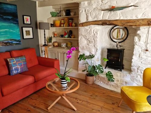 a living room with a red couch and a fireplace at An Artist's Cottage in Fishguard
