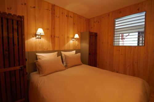Schlafzimmer mit einem Bett mit Holzwänden und einem Fenster in der Unterkunft les jardins de la sud in Lacanau