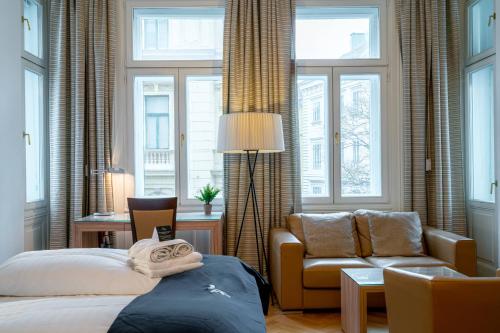 a bedroom with a bed and a couch and windows at Vienna Residence, City Hall - Parliament in Vienna