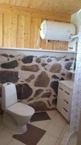 a bathroom with a toilet and a stone wall at Vakari Puhketalu in Vakari