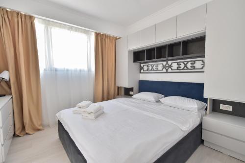 een slaapkamer met een bed met witte lakens en een raam bij WAVE 3 Promenada Apartments in Mamaia Nord – Năvodari