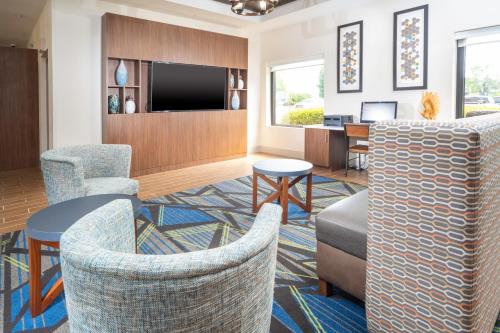 a lobby with chairs and a flat screen tv at Holiday Inn Express Clayton Southeast Raleigh by IHG in Garner