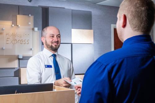 a man is talking to a man in a room at Holiday Inn Express Clayton Southeast Raleigh by IHG in Garner