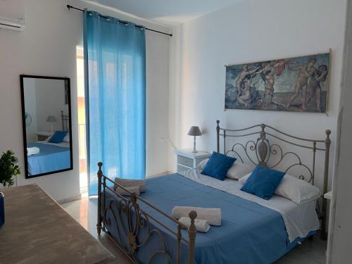 Schlafzimmer mit einem Bett mit blauer Bettwäsche und einem Spiegel in der Unterkunft Casa Mercede in Palermo