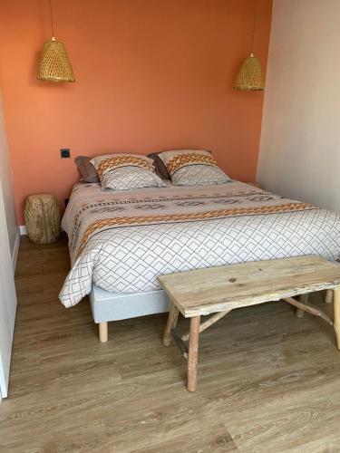 een slaapkamer met een bed en een houten tafel bij La Petite Mer in Riantec