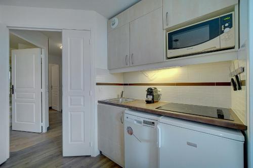 une cuisine avec des armoires blanches, un évier et un micro-ondes dans l'établissement IMMOGROOM - 2 Rooms renovated - Pool - Terrace - Garden - Parking -, à Cannes