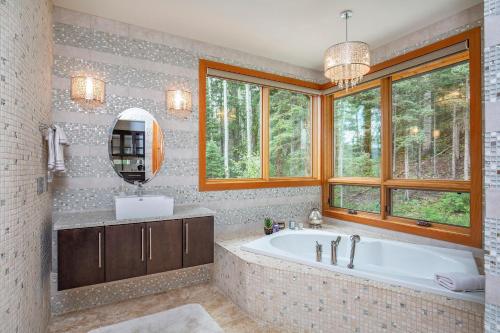 uma casa de banho com uma banheira, um espelho e janelas em Twilight 192 Tacoma Drive em Durango Mountain Resort
