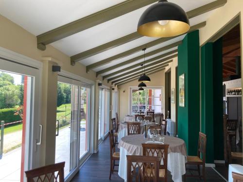 un comedor con mesas, sillas y ventanas en La Foresteria Canavese Golf & Country Club, en Torre Canavese