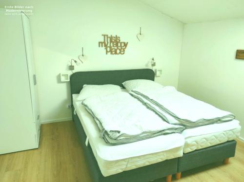 a small bedroom with a bed with white sheets at Wellness Ferienwohnung Waldblick in Kellenhusen