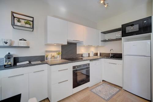 une cuisine blanche avec des armoires et des appareils blancs dans l'établissement IMMOGROOM - Close beaches - Terrace with sea view - pool -AC, à Cannes