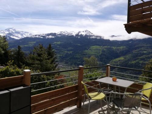 a balcony with a table and chairs and mountains at Maison de l'Epine -spa- Versant du soleil in Granier