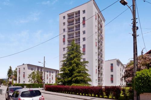 un immeuble d'appartements blanc avec une voiture garée devant. dans l'établissement Appartement Malva - Welkeys, à Annecy