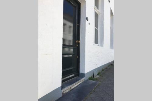 una puerta negra en un lado de un edificio blanco en Stadsvilla met patio in centrum Maastricht en Maastricht