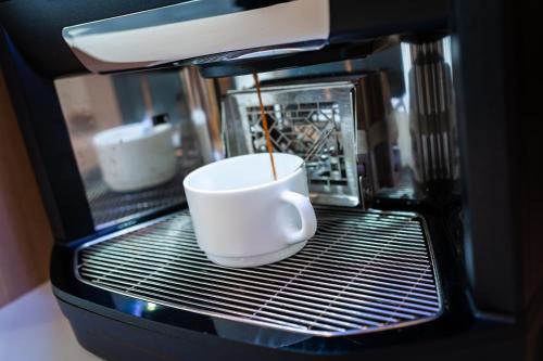 a coffee cup is sitting in a microwave at Premiere Classe Beaune in Beaune