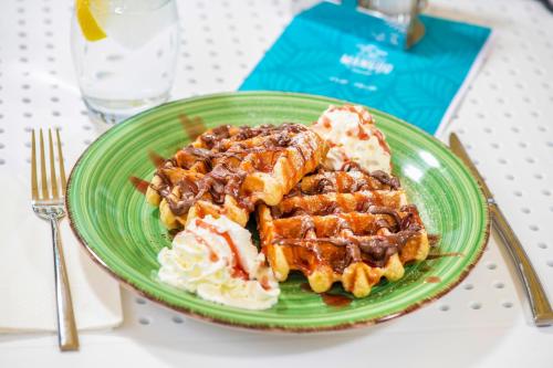 a green plate of food with waffles and whipped cream at BalaLake Resort in Szántód