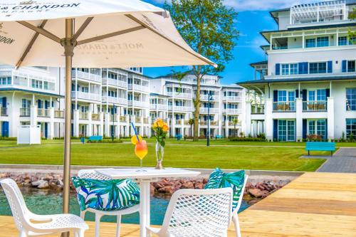 a table with an umbrella and chairs and a building at BalaLake Resort in Szántód