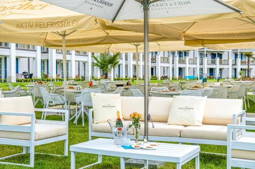 a row of white chairs and tables with umbrellas at BalaLake Resort in Szántód