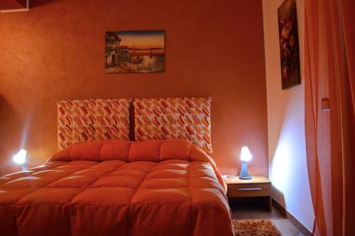 a bedroom with a bed with orange walls and two lamps at A due passi dal mare in Capo dʼOrlando