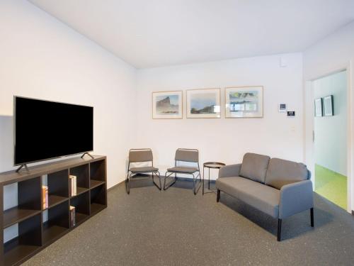 sala de estar con TV de pantalla plana y sillas en Modern holiday home in Scherpenheuvel with infrared sauna, en Scherpenheuvel-Zichem
