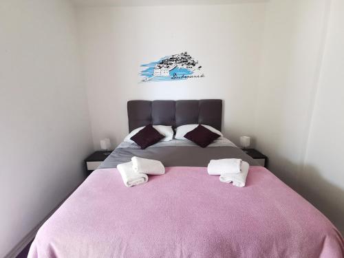een slaapkamer met een roze bed en 2 handdoeken bij Apartment Lira 2 in Mlini