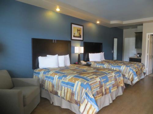 une chambre d'hôtel avec deux lits et une chaise dans l'établissement Black Gold Inn, à Yoakum